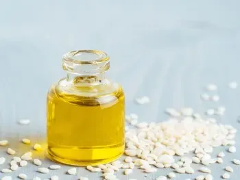 Petit flacon d’huile de sésame posé près de graines claires